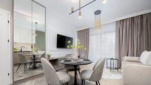 A modern living room with a dining area, a sofa, and a TV mounted on the wall. - Practical Studio in Mokotow | Parking | Desk (Warszawa)