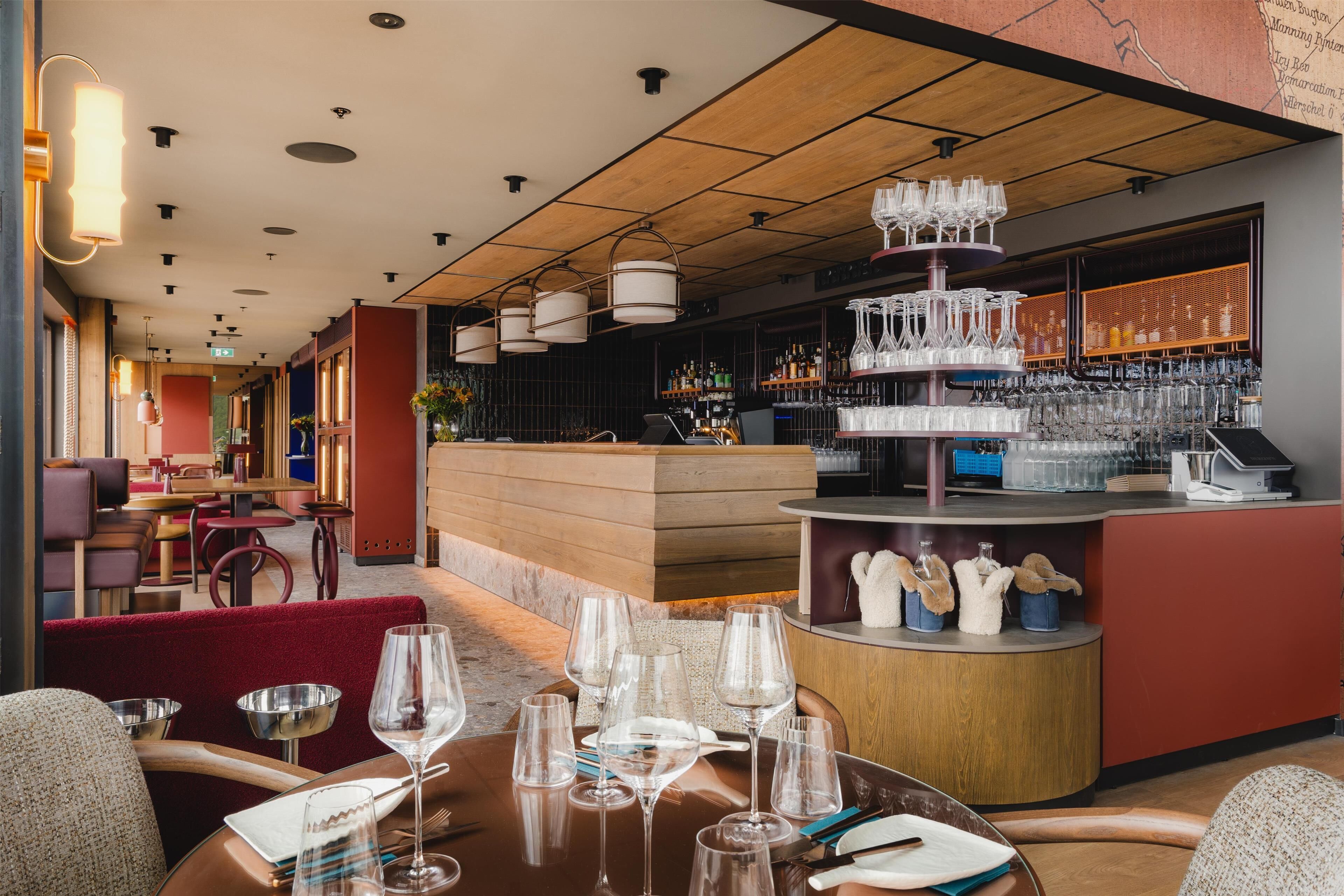 A restaurant interior with a bar area, seating arrangements, and a variety of glassware.