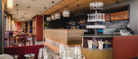 A restaurant interior with a bar area, seating arrangements, and a variety of glassware.