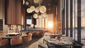 A modern restaurant with high ceilings, pendant lighting, and a view of the water. - The Dock 69°39 by Scandic (Tromsø)