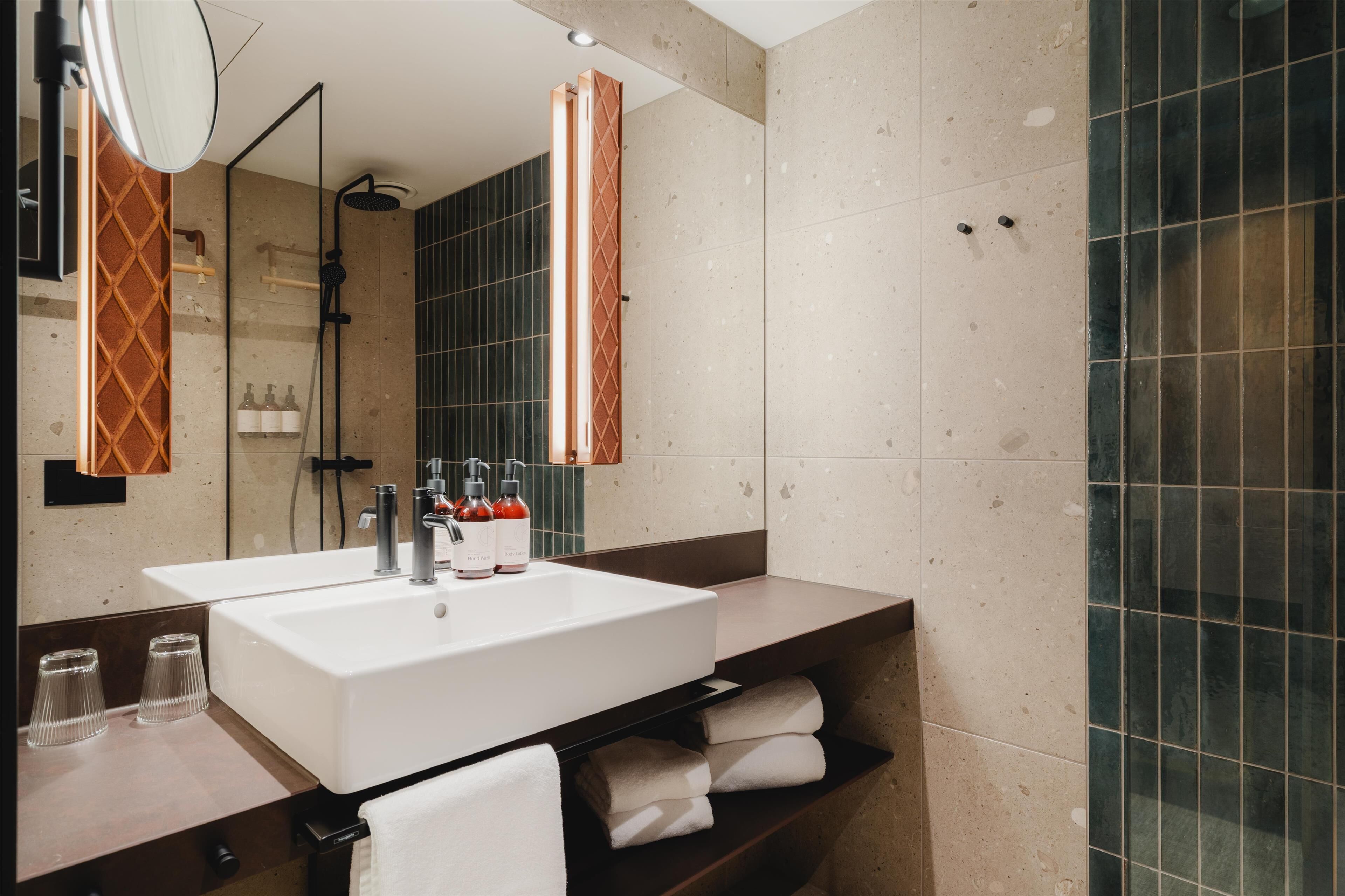 A modern bathroom with a large sink, mirror, and towel rack.