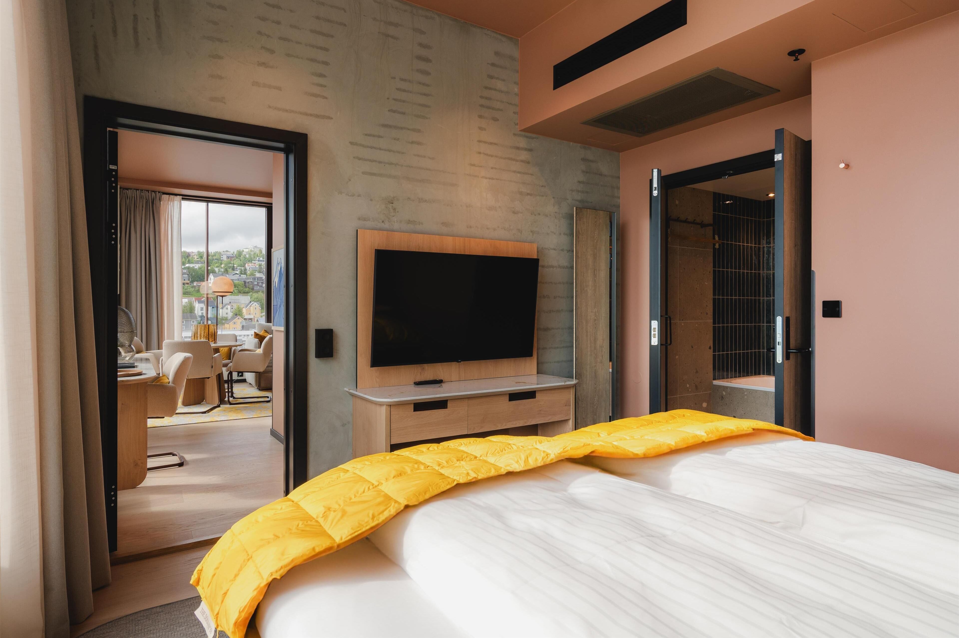 A hotel room with a bed, a TV, a desk, and a chair.