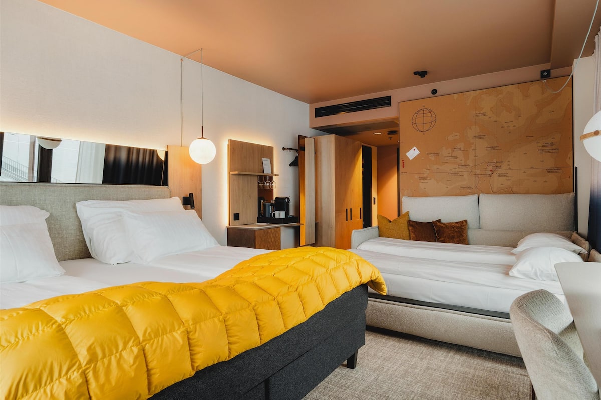 Une chambre d’hôtel avec un lit, un bureau, une chaise et une carte accrochée au mur.