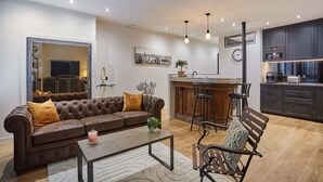 A modern living room with a brown leather sofa, a coffee table, and a bar area with stools. - Apartment in the Center of Paris by studioprestige (Paris)