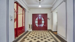 A hallway with a checkered floor, a red door with glass panels, and a ceiling light fixture. - Apartment in the Center of Paris by studioprestige (Paris)