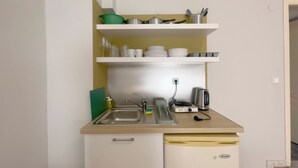 Una cocina compacta con un lavamanos, un tostador y un refrigerador pequeño.