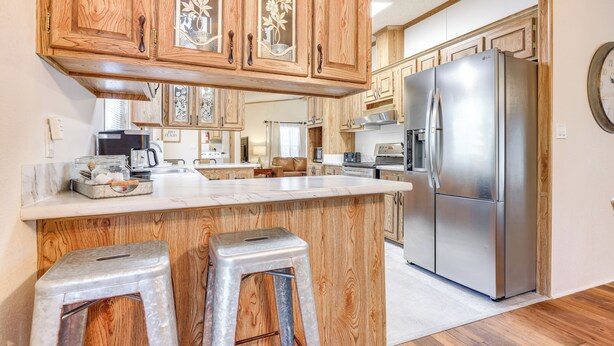 A kitchen with wooden cabinets, a stainless steel refrigerator, and a marble countertop. - Relax, Swim & Explore: Home in Wimberley! (Wimberley)