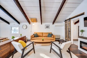 Una sala de estar con techo de madera, un sofá, dos sillones, una mesa de centro y una chimenea.