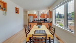 Une cuisine moderne avec des meubles en bois, un îlot central et un coin repas comprenant une table et des chaises.