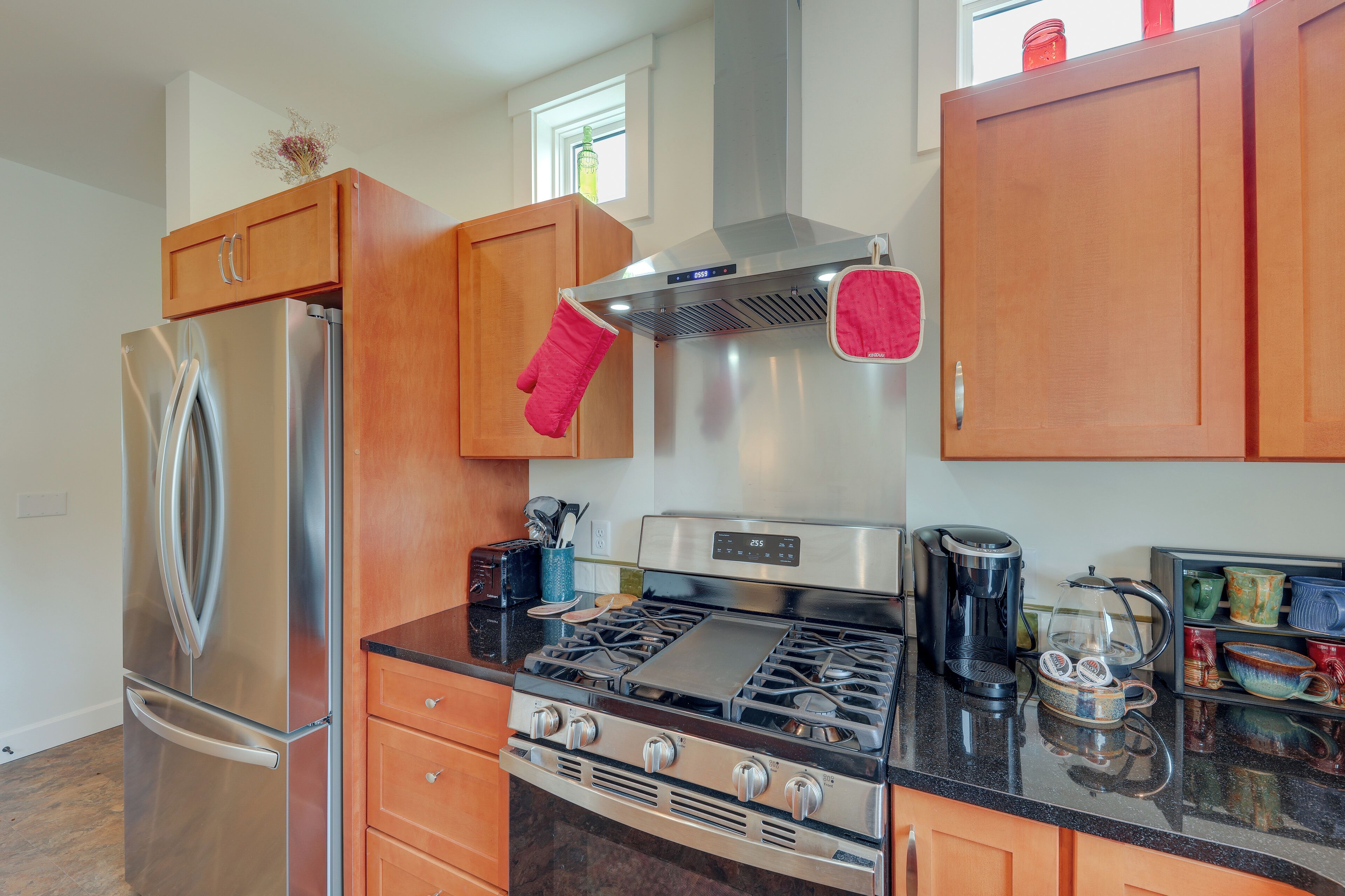 A modern kitchen with stainless steel appliances, wooden cabinets, and a gas stove.