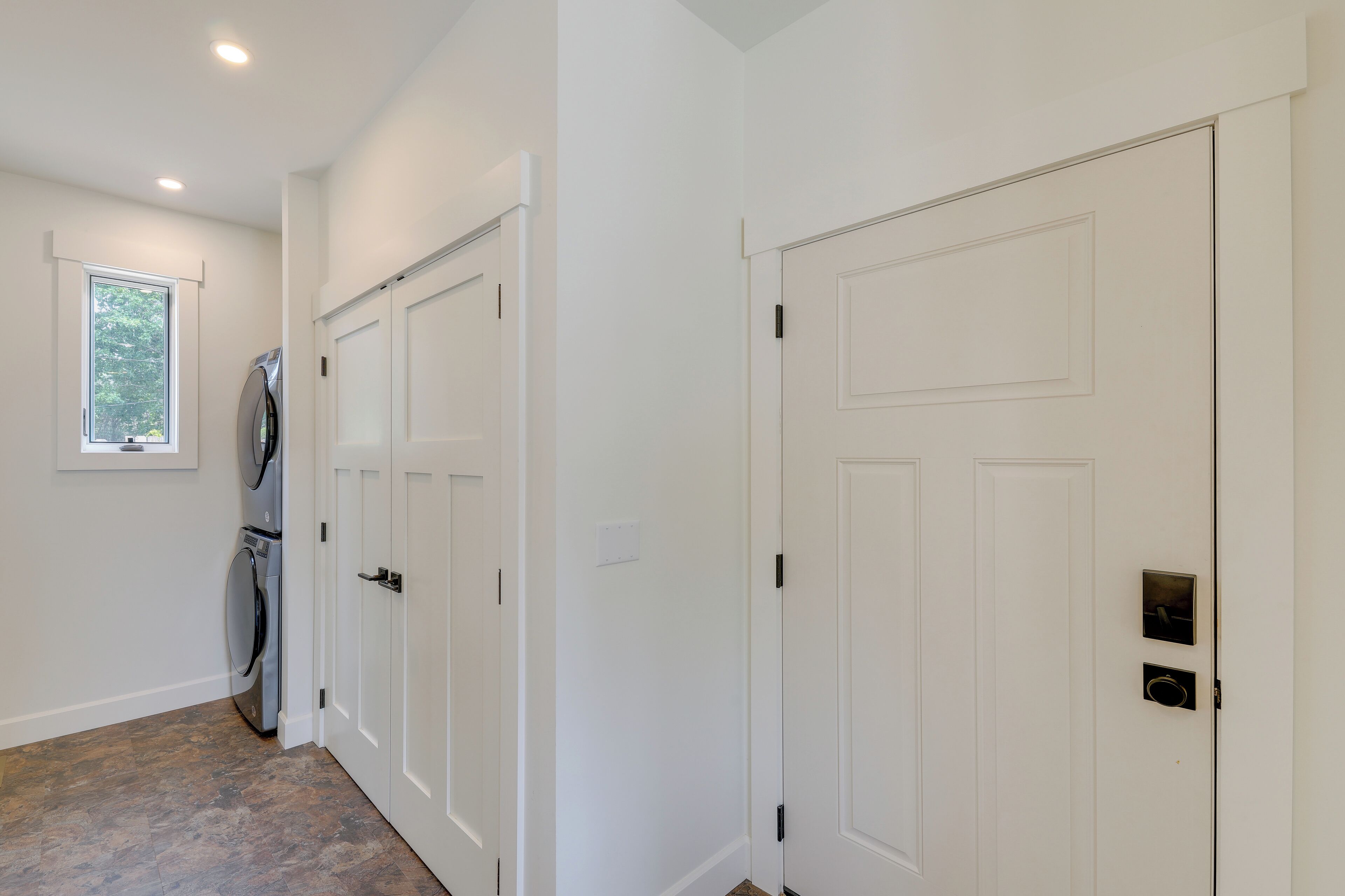 A hallway with white doors, a window, and a washing machine.