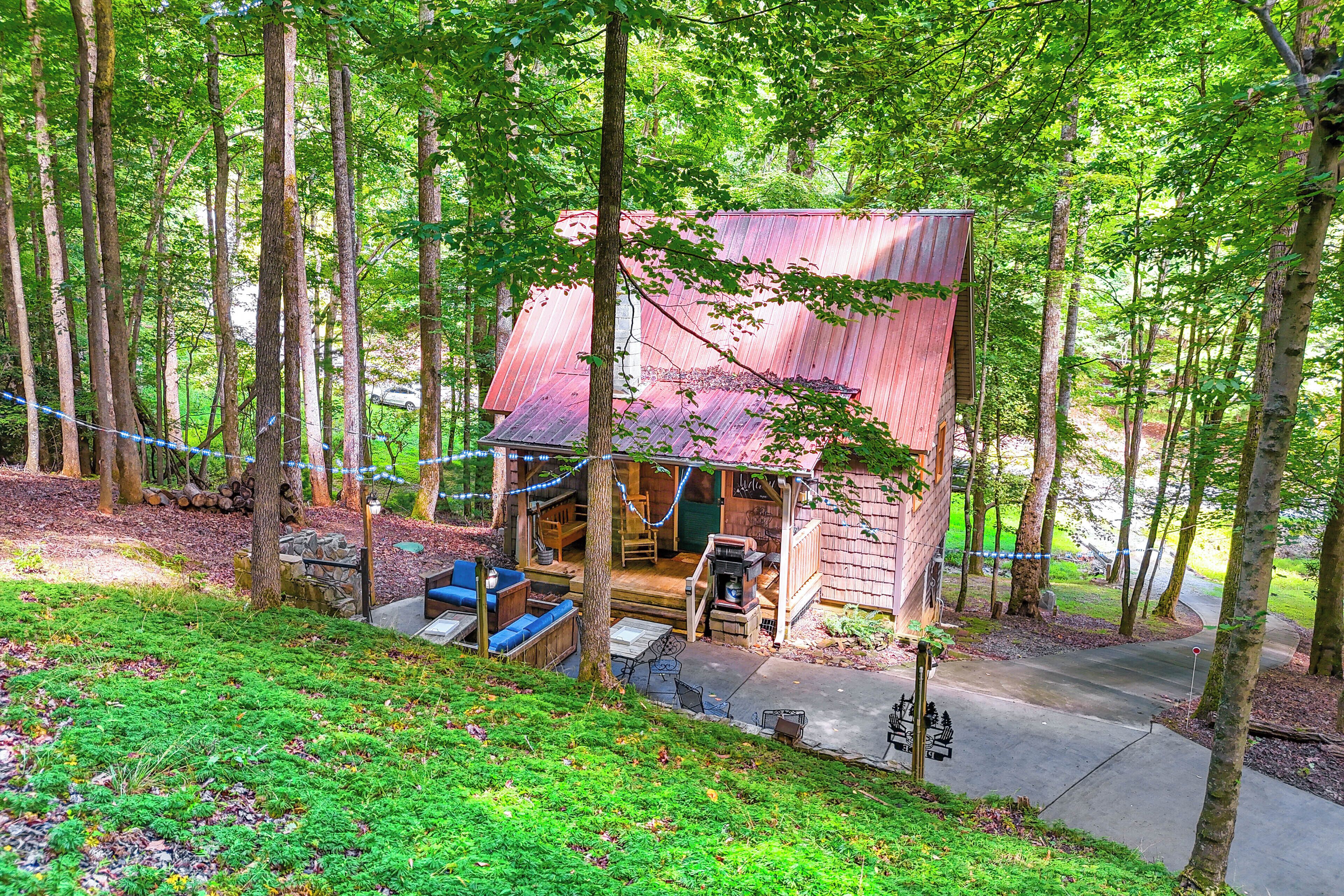 Un rustico chalet con veranda, circondato da alberi alti.