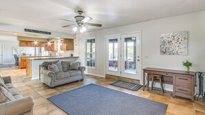 A spacious living area with a sofa, a coffee table, a dining table with chairs, and a kitchen in the background. - Waterfront Kansas Home w/ Private Fire Pit! (Arkansas City)
