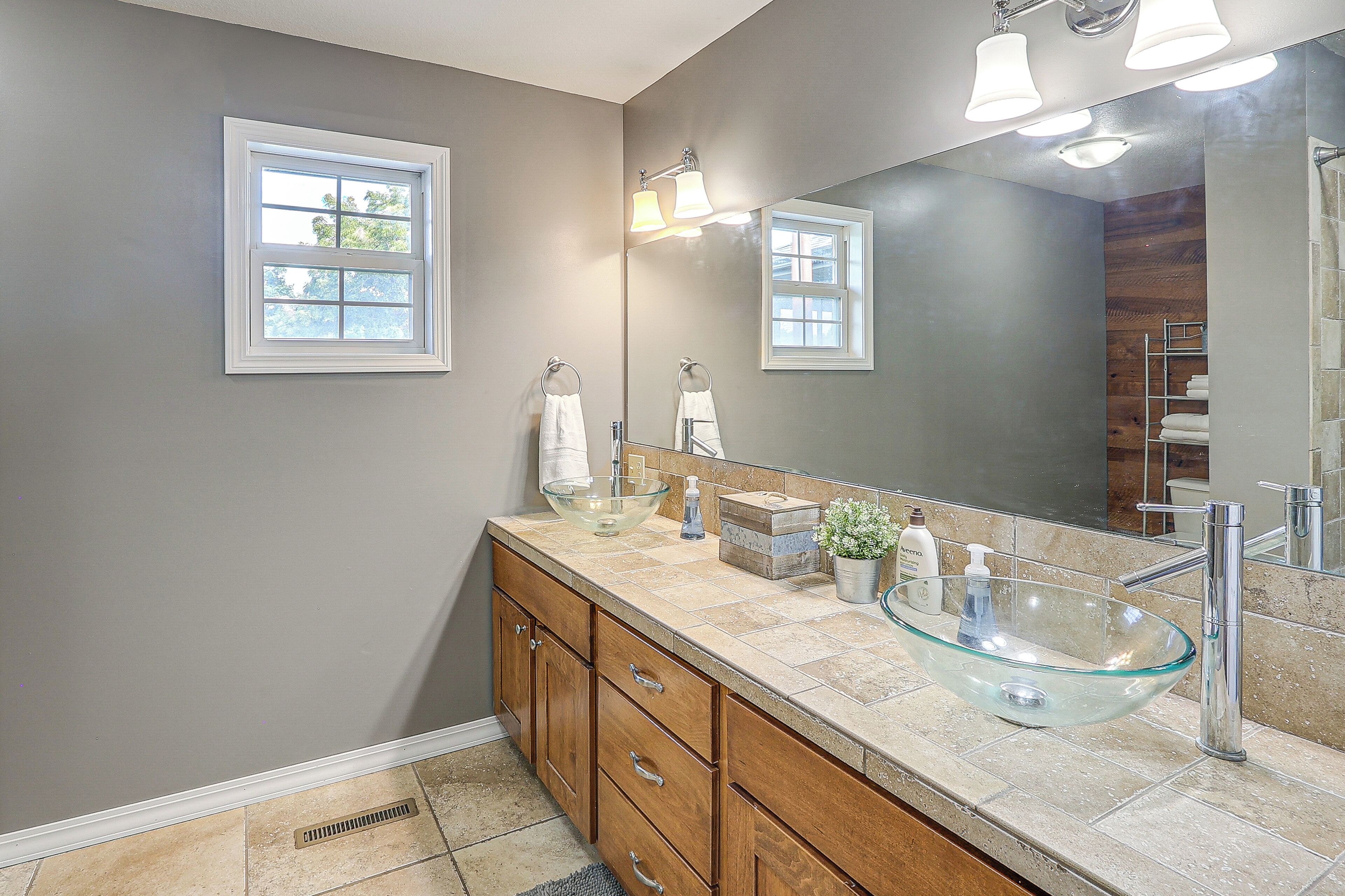 A modern bathroom with a glass vessel sink, wooden vanity, and a large mirror.