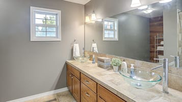 A modern bathroom with a glass vessel sink, wooden vanity, and a large mirror.