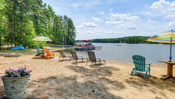 Un cadre idyllique au bord du lac, avec un bateau amarré, entouré de chaises et de parasols, et une plage de sable.