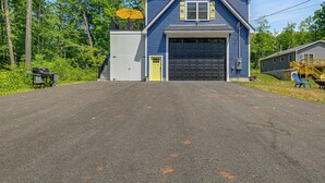 Un bâtiment à deux étages avec un garage, entouré d’arbres.