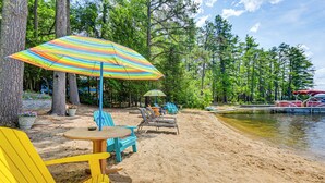 Un cadre idyllique au bord de la plage, avec des parasols rayés aux couleurs vives, des chaises de plage et une petite table en bois.