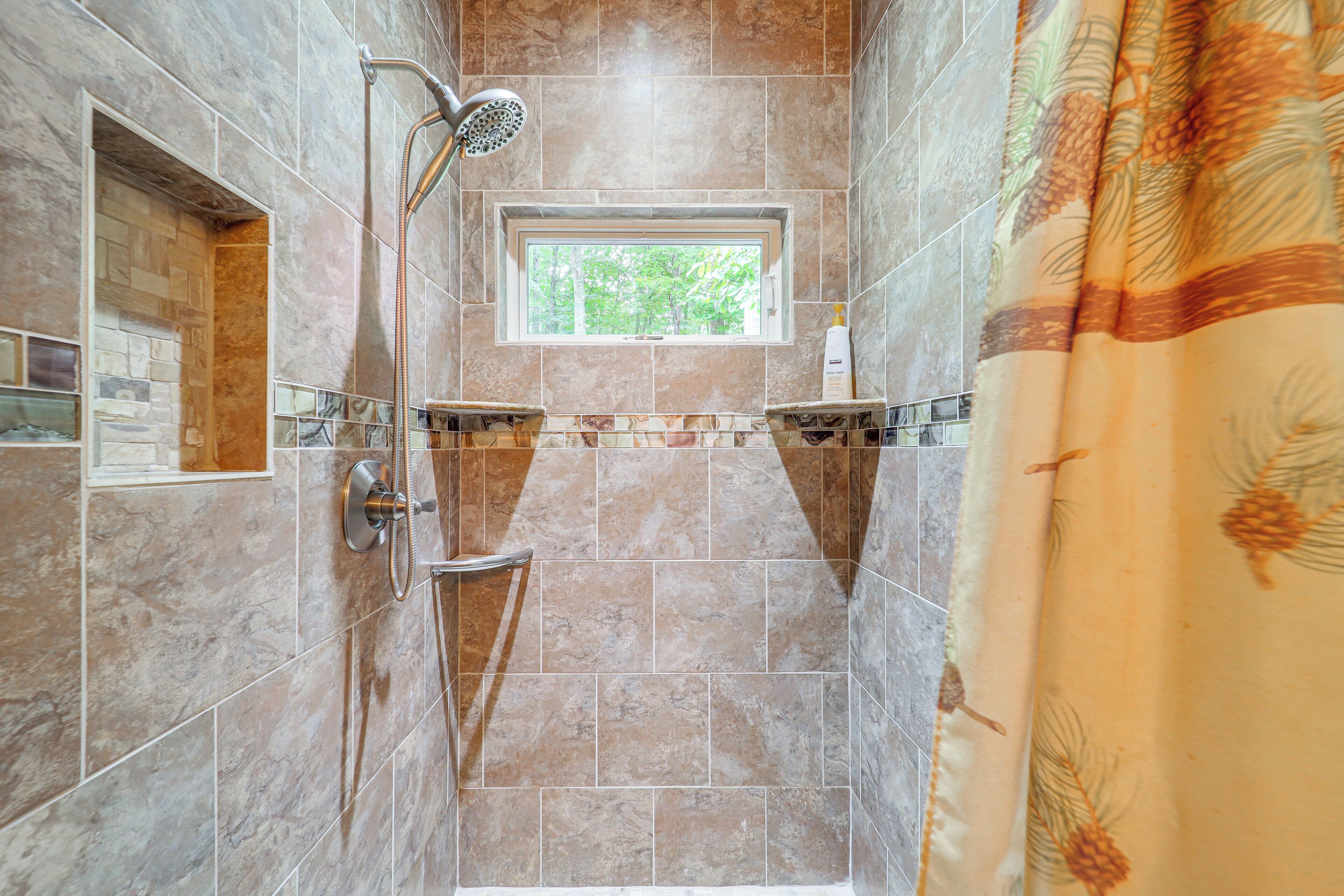 A shower with a window, tiled walls, and a showerhead.
