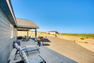Un porche cubierto con mobiliario exterior, una parrilla y vistas a un paisaje rural.