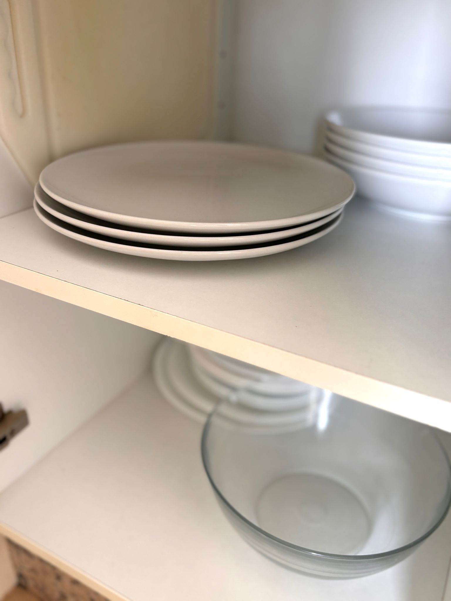A stack of white plates on a shelf.