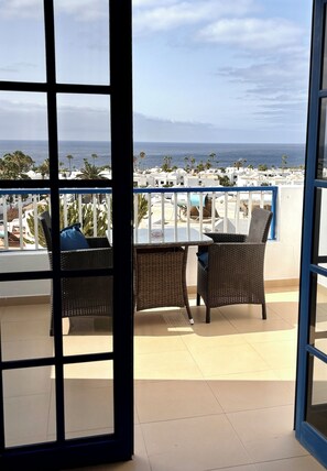 Enjoy breathtaking sea views from this balcony with comfortable seating and a small table.