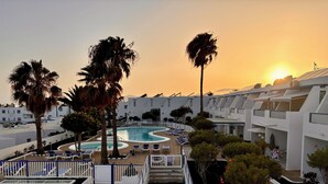 A resort with a swimming pool, palm trees, and white buildings.