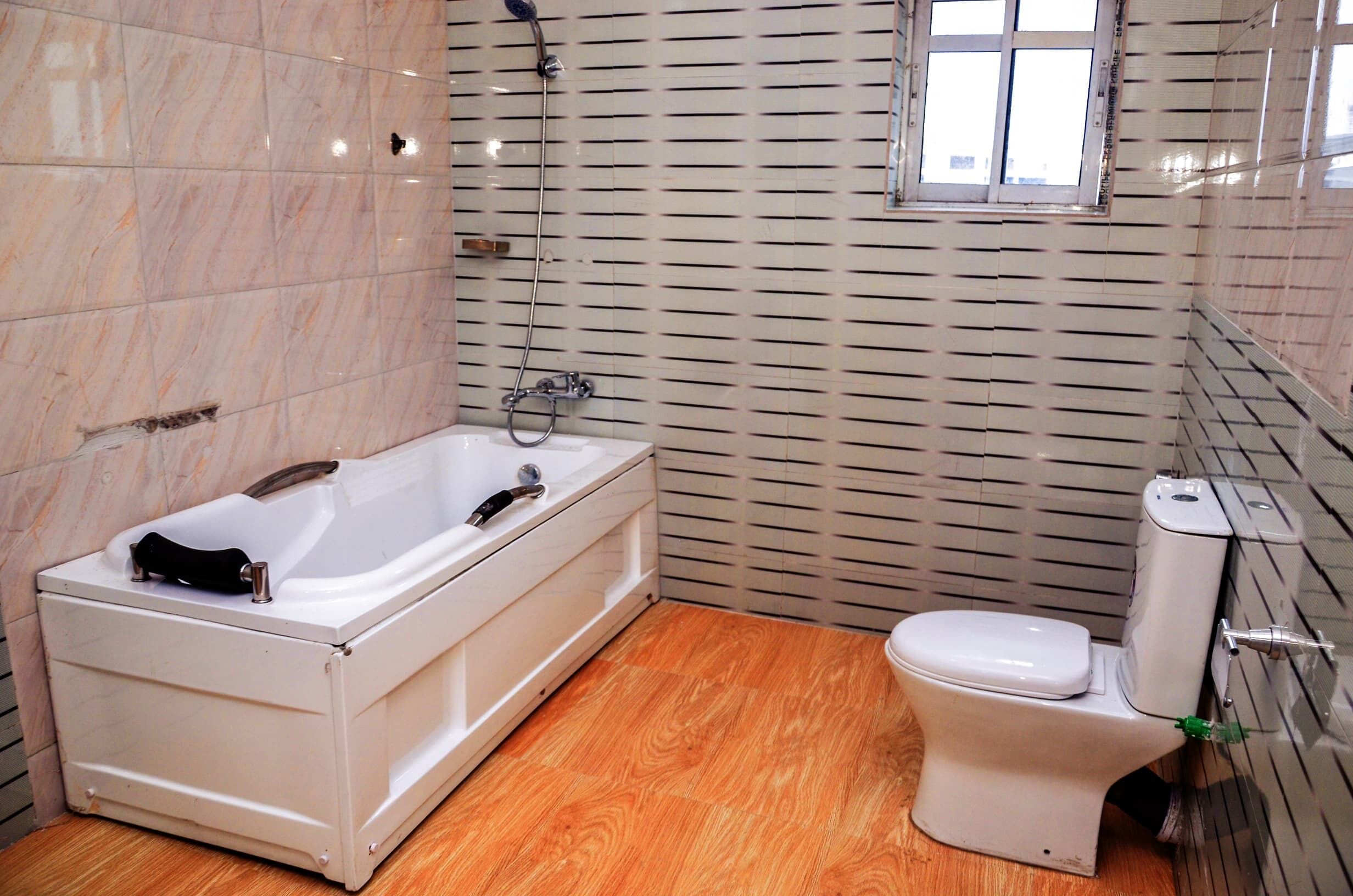 Et badeværelse med badekar, toilet og et vindue.