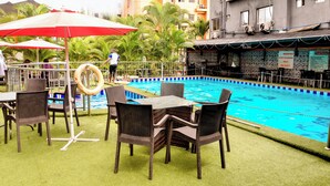 Area piscina con tavolo e sedie, delimitata da una recinzione e palme.