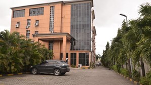 Un edificio dal design architettonico moderno, caratterizzato da un mix di vetrate e pannelli solidi, con un vialetto lastricato e un'auto parcheggiata.