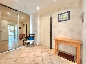 Enter a cozy room with a comfortable chair and a bench, featuring a framed picture and a door leading to a kitchen area.