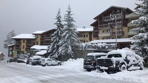 A snow-covered building with multiple balconies and a large tree in front. - Cozy 2-Room Apt for 6 with Terrace, Ski Access, Pet-Friendly, Central Location in Plan Peisey (Peisey-Nancroix-Plan Peisey)