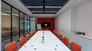 A conference room with a long table, orange chairs, a whiteboard, and a screen displaying 'TULIP'.