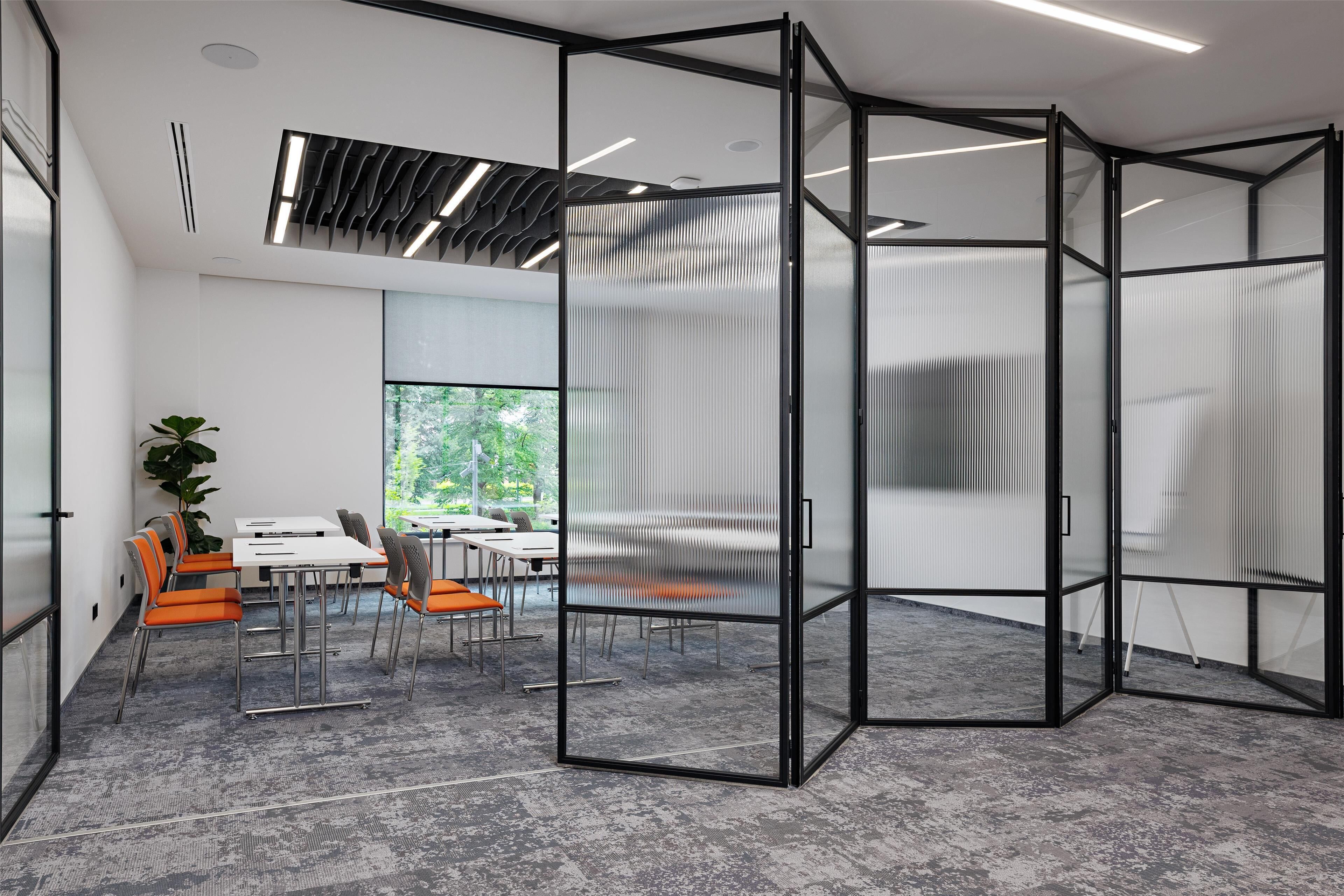 A modern meeting room with glass partitions, a whiteboard, and a view of greenery outside.