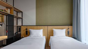 Habitació d'hotel amb dos llits, escriptori, biblioteca i finestra gran amb cortines.