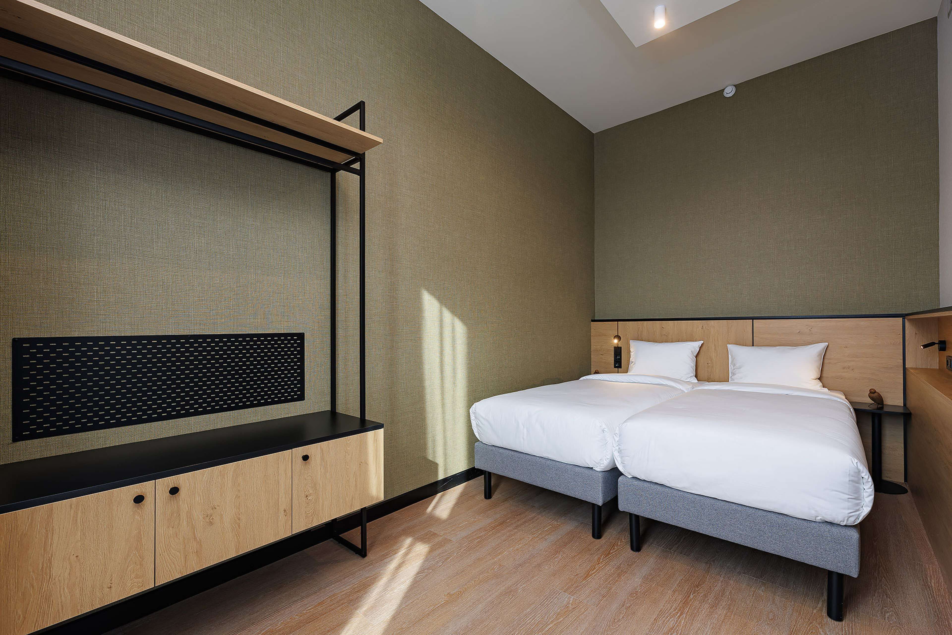 Una habitación de hotel moderna con cama, escritorio y televisor montado en la pared.