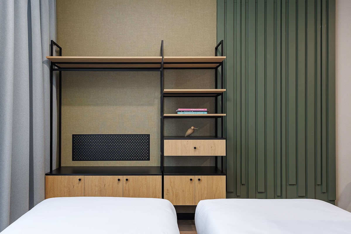 Un dormitorio moderno con cama empotrada, un armario de madera y una estantería con libros y una figurita de pájaro.