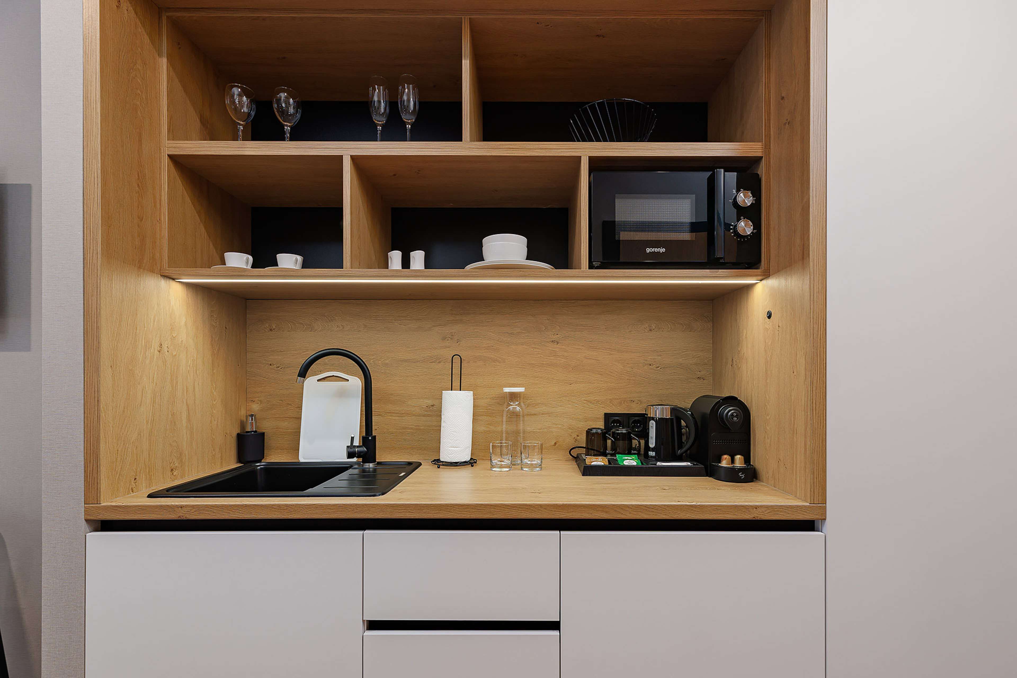 A compact kitchen with a wooden countertop, a sink, a microwave, and a coffee maker.