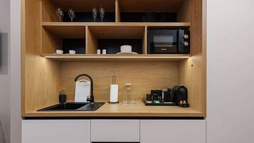 A compact kitchen with a wooden countertop, a sink, a microwave, and a coffee maker.