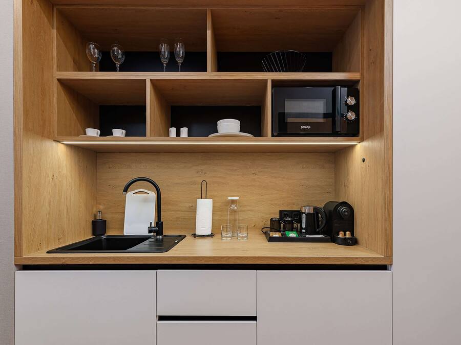 A compact kitchen with a wooden countertop, a sink, a microwave, and a coffee maker.