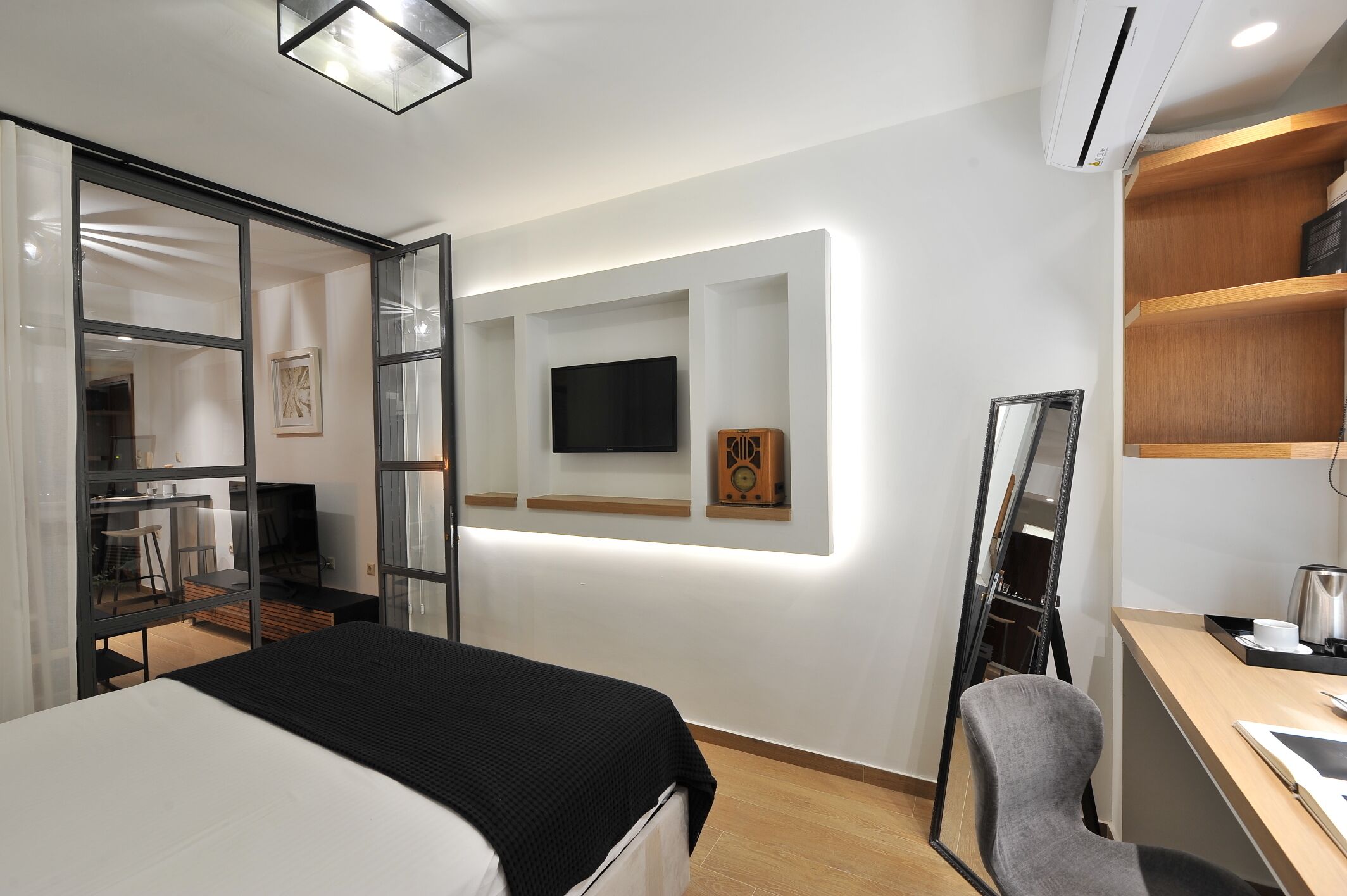 Une chambre d’hôtel moderne équipée d’un lit, d’un bureau et d’un téléviseur fixé au mur.