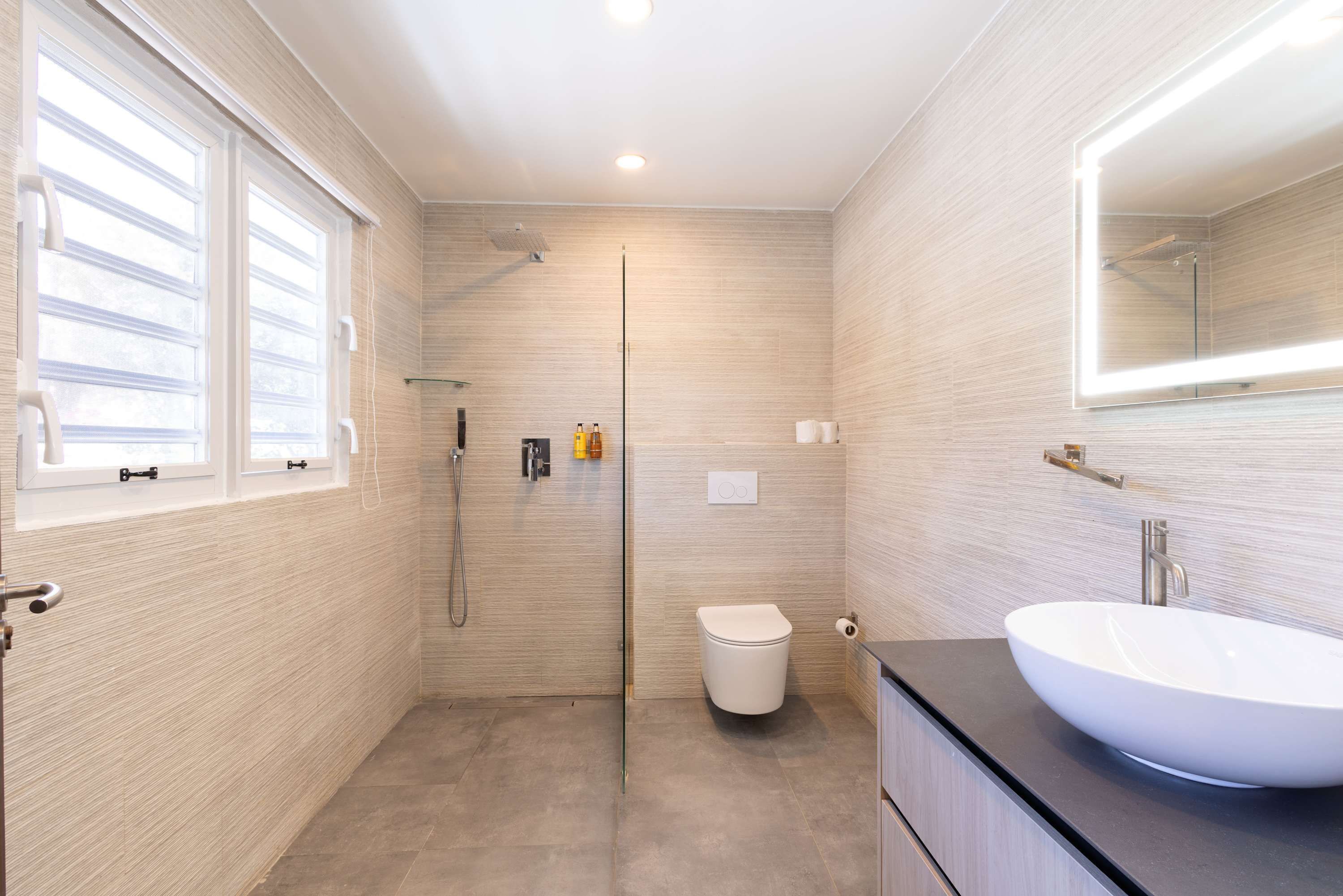 Un bany modern amb un mirall gran, un lavabo blanc i una dutxa.