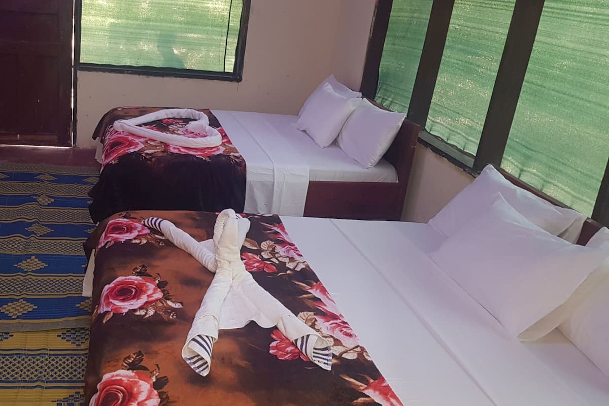 Una habitación con dos camas, una mesa y un tapete estampado.