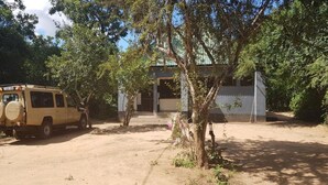A building with a dirt driveway and a parked vehicle. - Camp Seluu (Mloka)