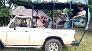 A white off-road vehicle with a roof and side curtains, parked in a grassy area. - Camp Seluu (Mloka)