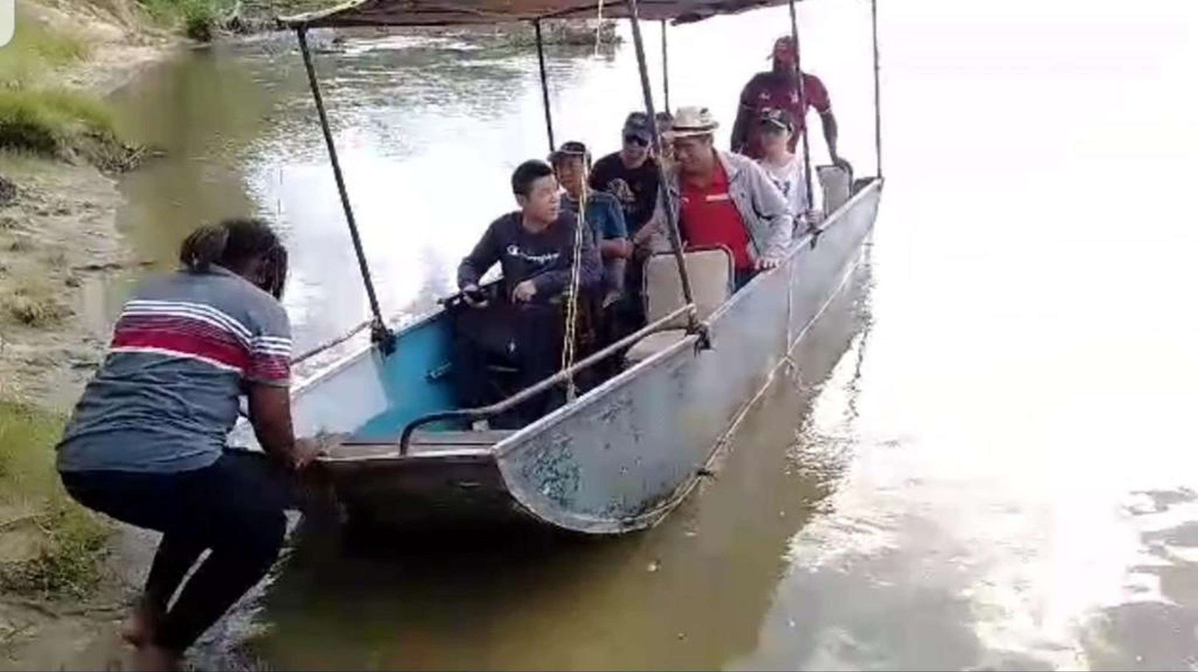 A group of people in a small boat on a river.