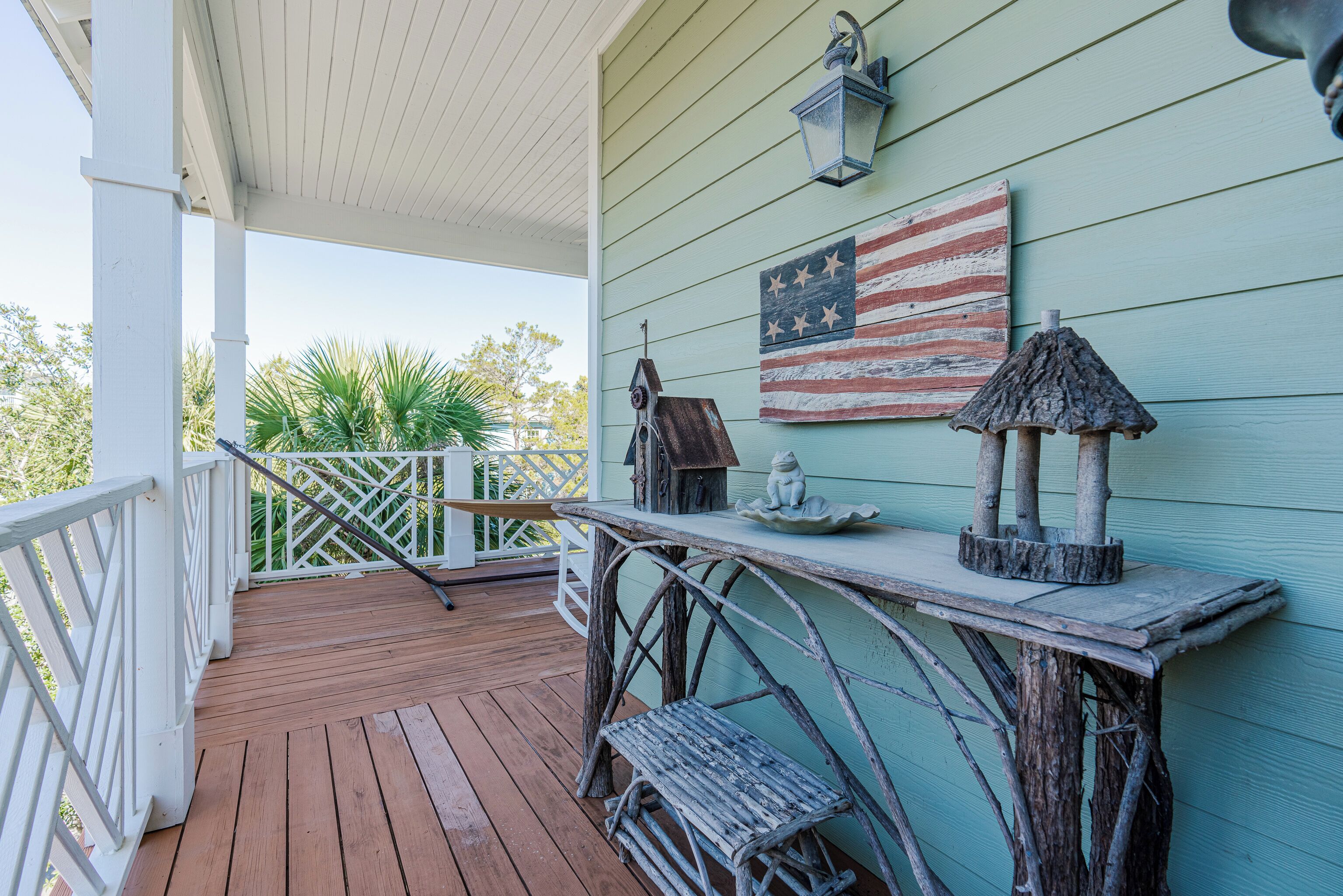A wooden deck with a railing, a rustic table, and a wall-mounted American flag.