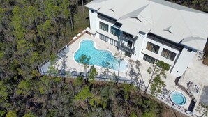 An aerial view of a modern house with a large swimming pool, surrounded by a forested area. - Pinewood30a 145 (Santa Rosa Beach)