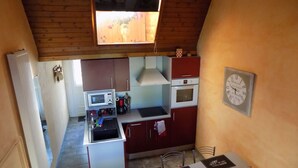 A compact kitchen with a microwave, oven, and a small island. - Location Saisonnière en Bord de Loire (Coubon)