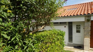 A white building with a tiled roof, a white door, and a small window. - Location Saisonnière en Bord de Loire (Coubon)